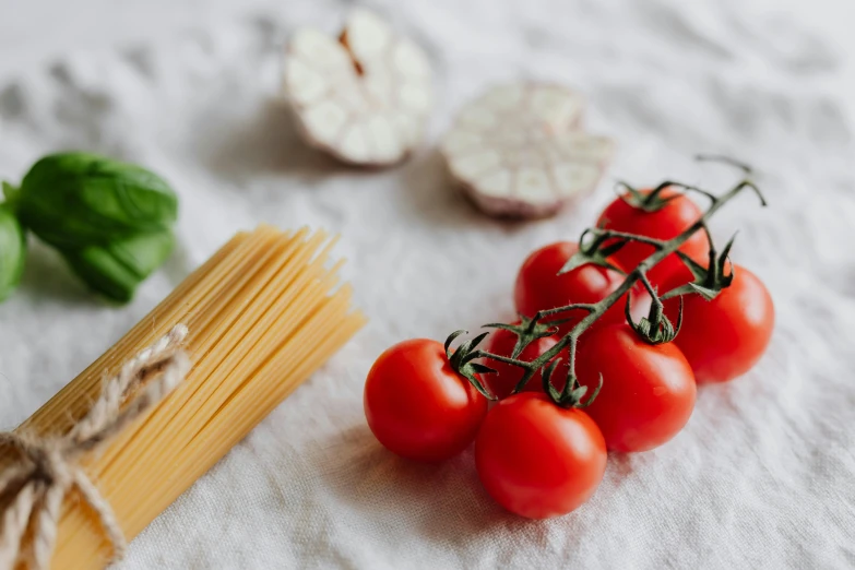 tomatoes sitting on a plate next to a slice of spaghetti