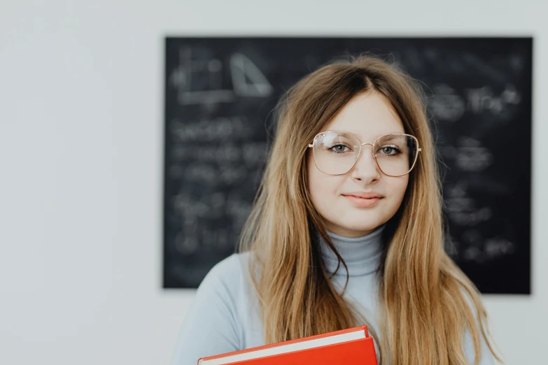 a woman wearing glasses, holding an orange folder