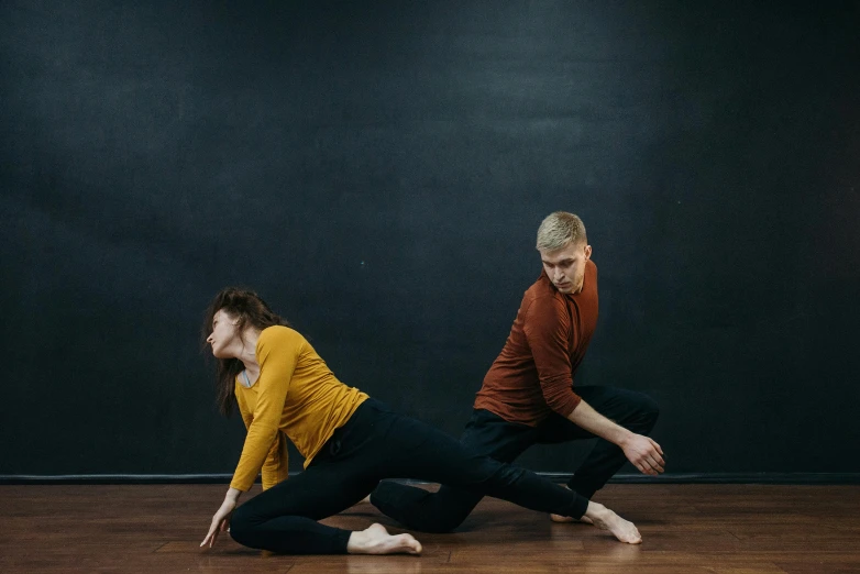 two people are performing dance moves on a wooden floor