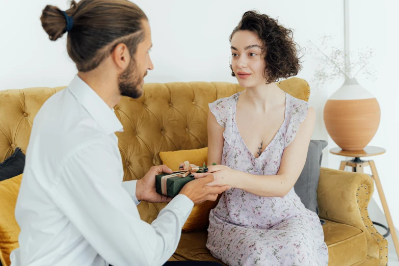 a man handing soing to a woman on a couch