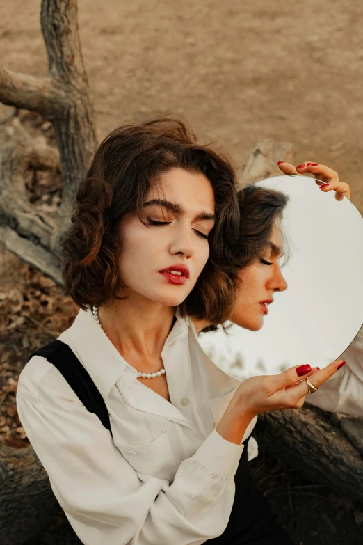 a woman looks into a mirror while another holds it