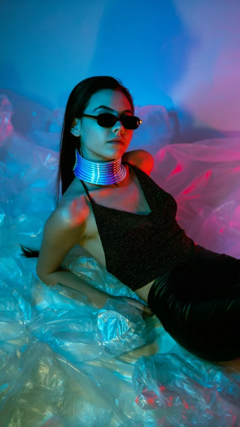woman laying in a bubble like area wearing a black top and silver collar