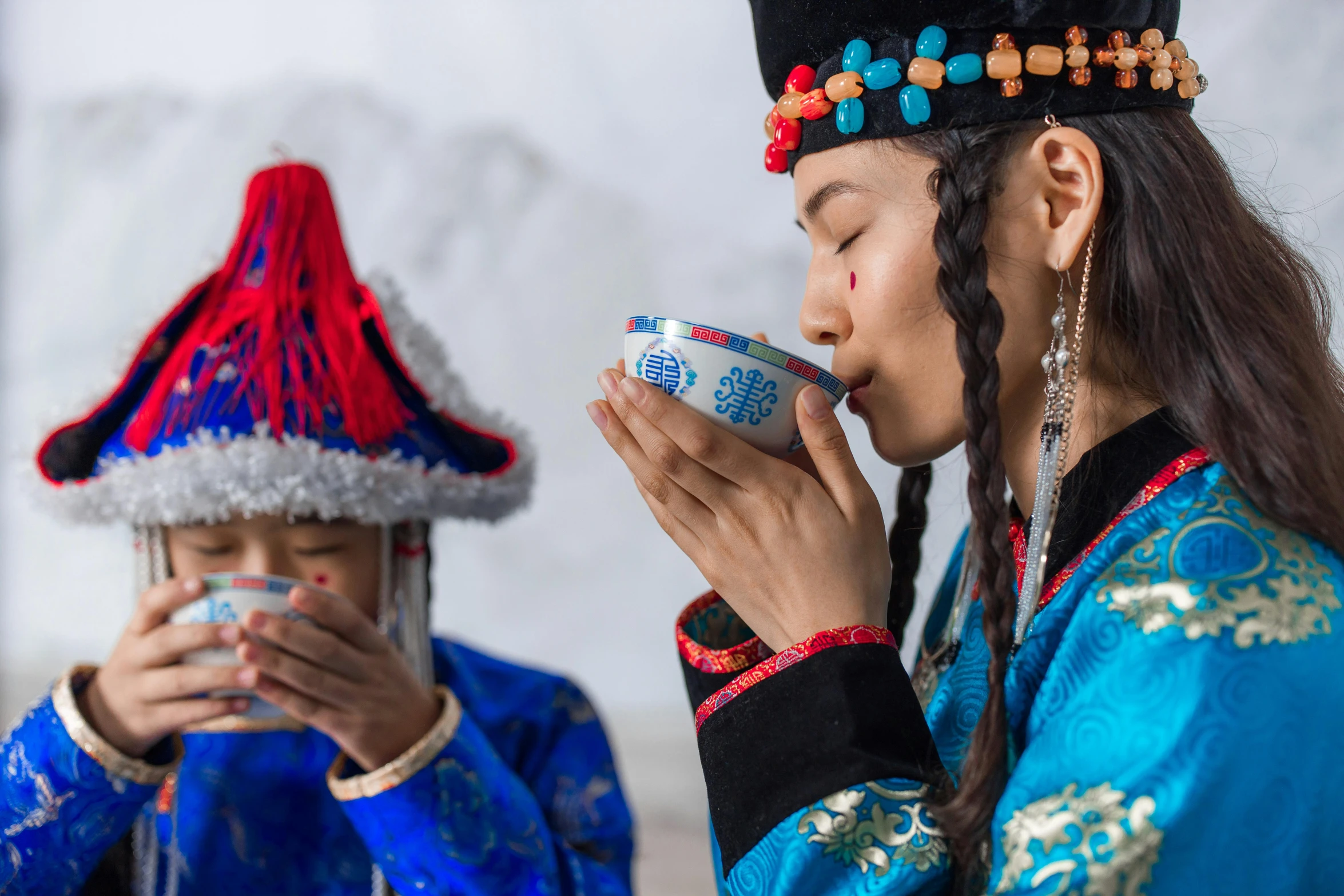 two people dressed in ethnic garb drinking from cups