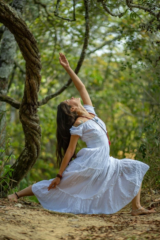 a woman leaning against a tree to catch a frisbee