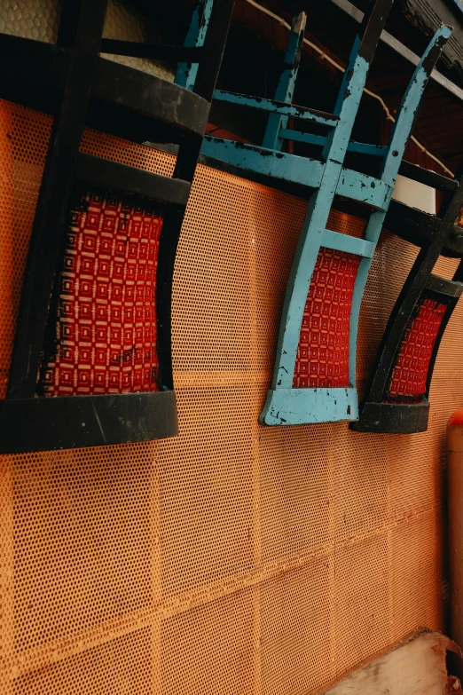 a set of four iron chairs and two orange cushions on a wooden bench