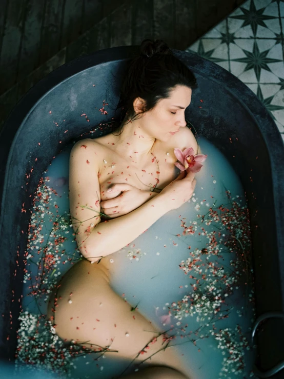 a woman laying in a bathtub that is covered in flowers