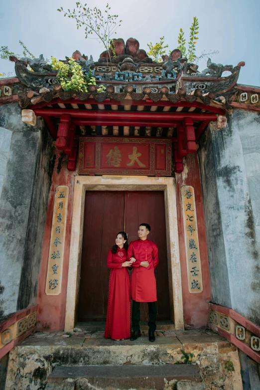 a couple poses for the camera with red coats on