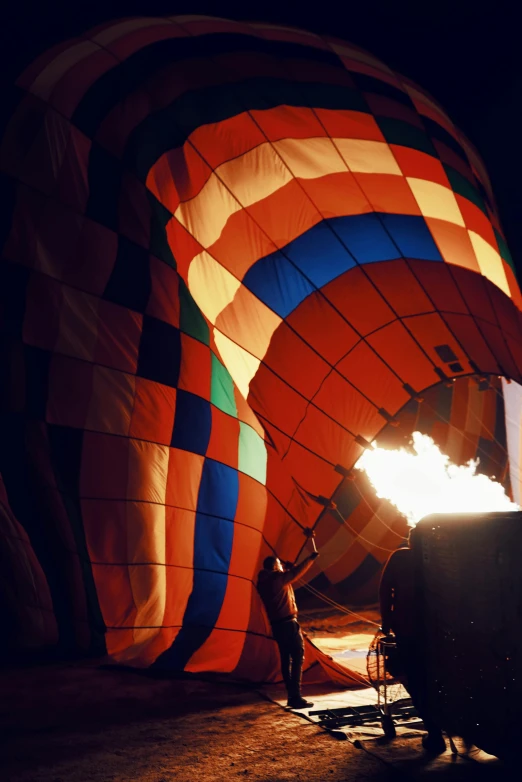 a man putting burning fuel in the inside of an air ballon