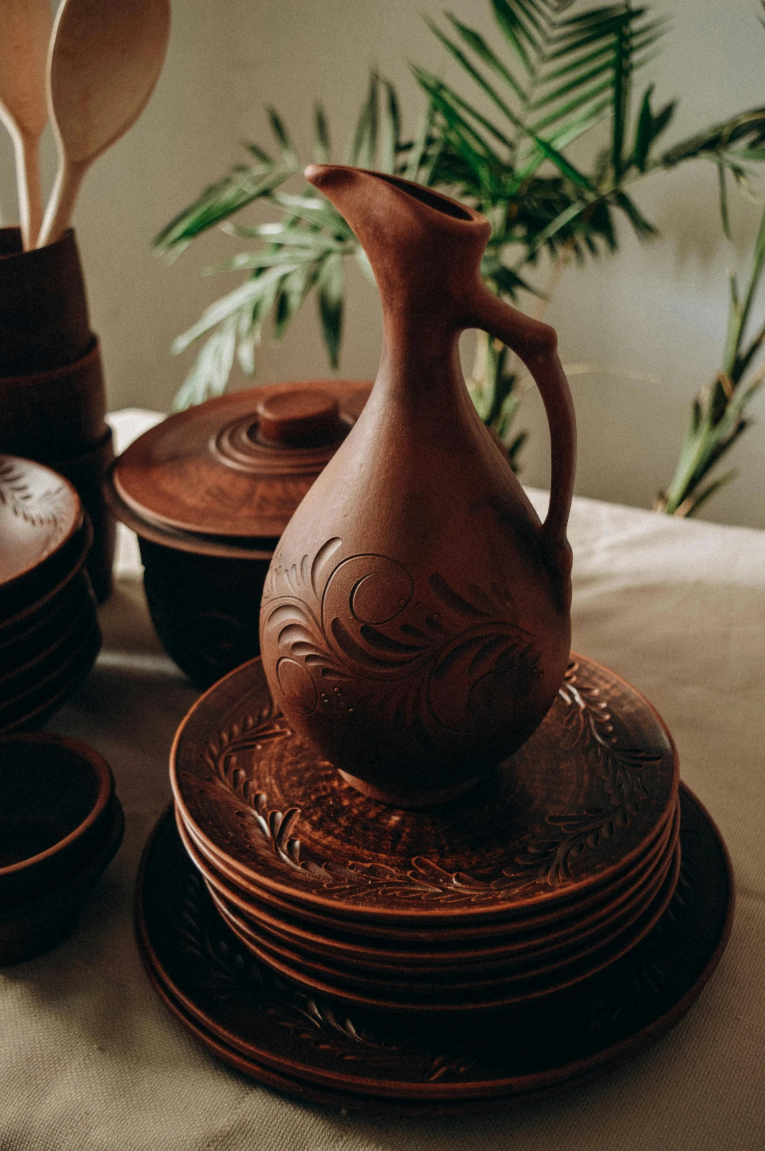 a brown jug next to plates and spoons