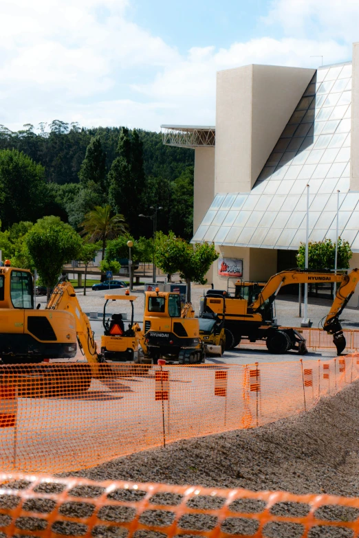 a row of bulldozers are sitting in the foreground of a building