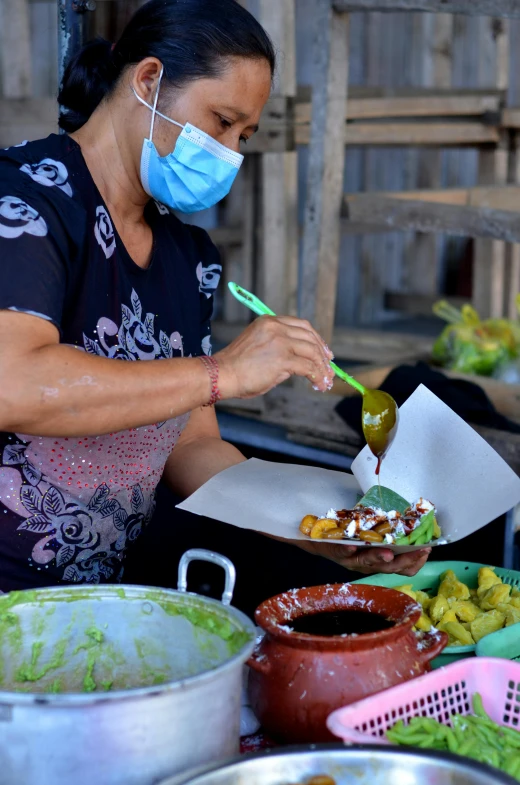 a woman in black shirt and face mask preparing food