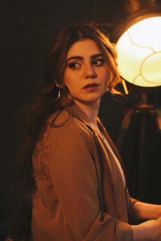 a beautiful young woman posing next to a light