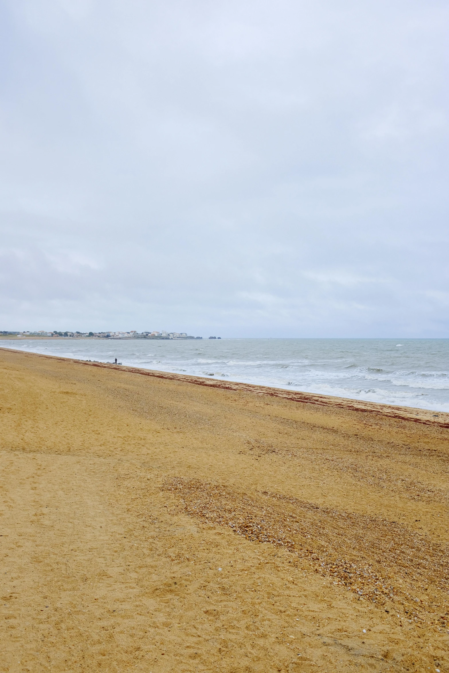 a man on a beach with surfboard in the distance