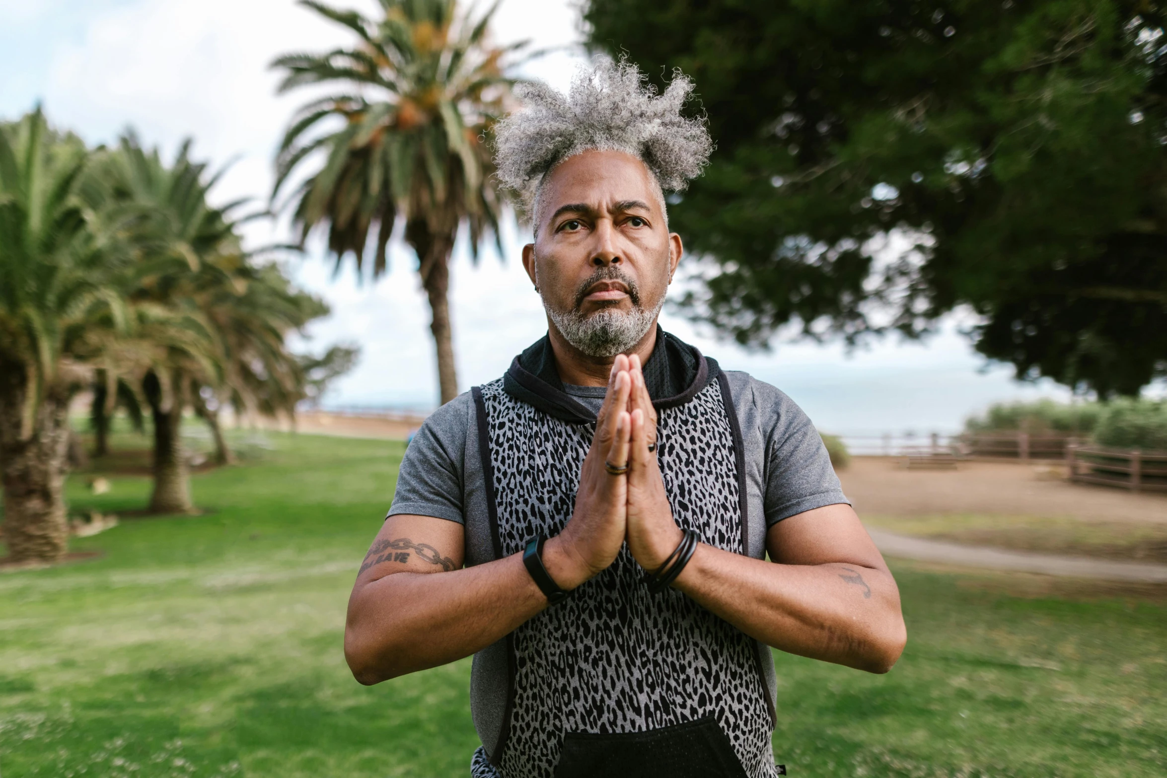 a man standing in a grassy area with his hands folded