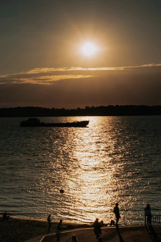 people and boats on the water at sunset