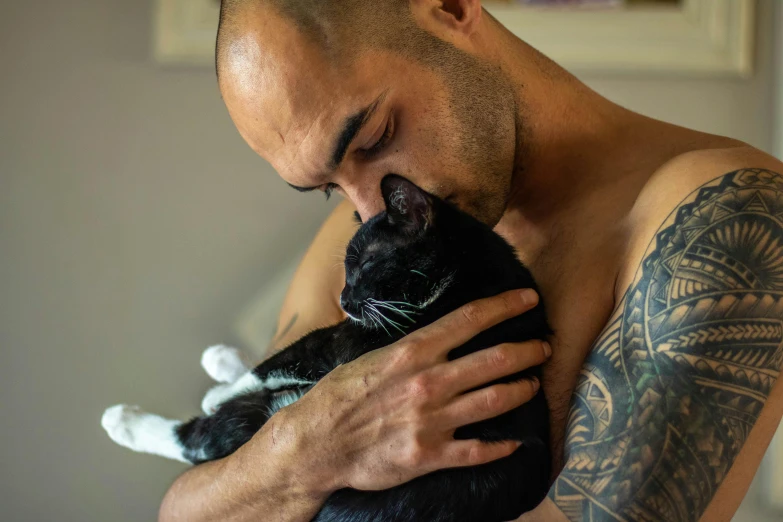 man holding black cat next to his face