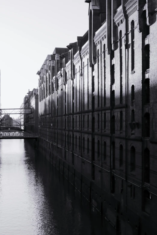 a river near a brick wall with buildings next to it