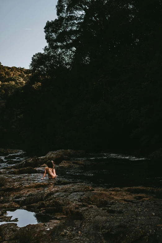 the woman is relaxing in the water on a rocky beach