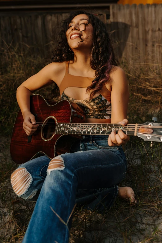 a girl with eye glasses sitting with her guitar outside