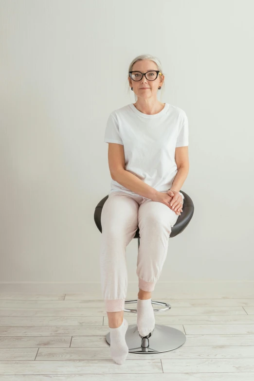 an older woman wearing glasses sitting on a hair dryer