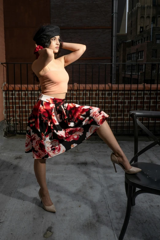 a woman is wearing an orange tank top and floral skirt while sitting on a bench