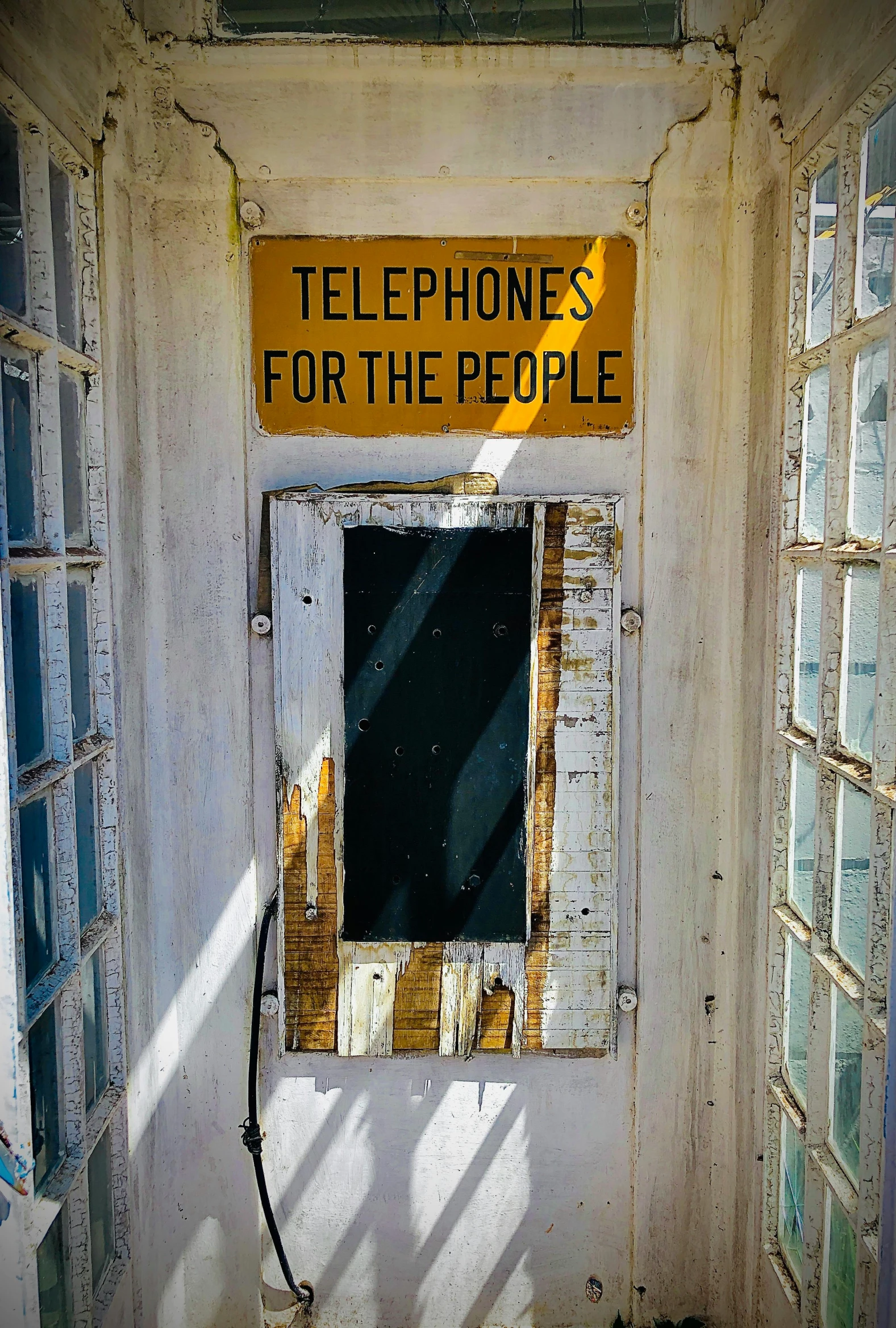 a broken window with a sign reading telephone for the people