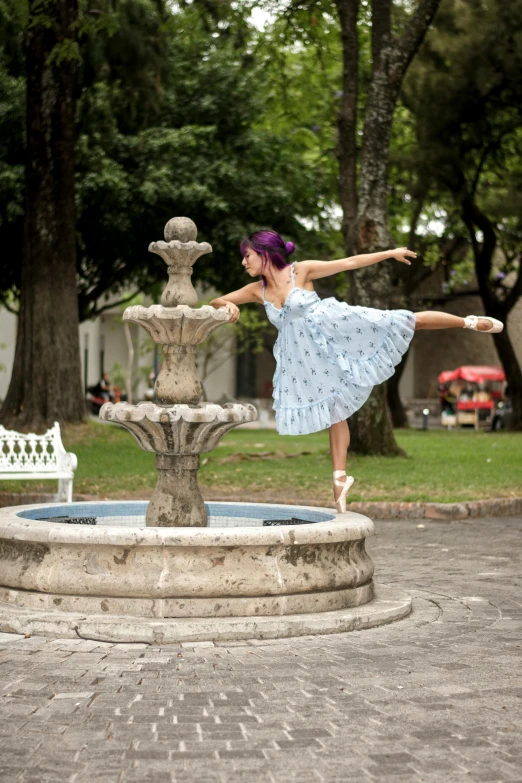 a woman standing by a water fountain with her arms out