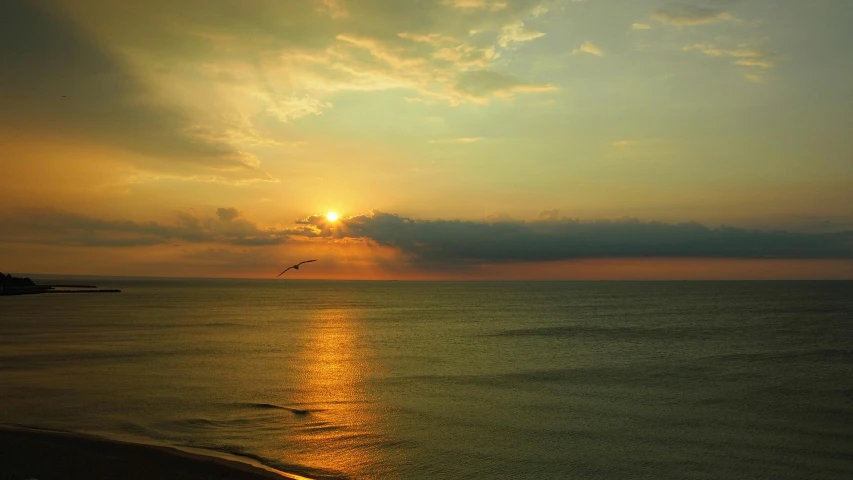 the sun is shining through the clouds at the beach