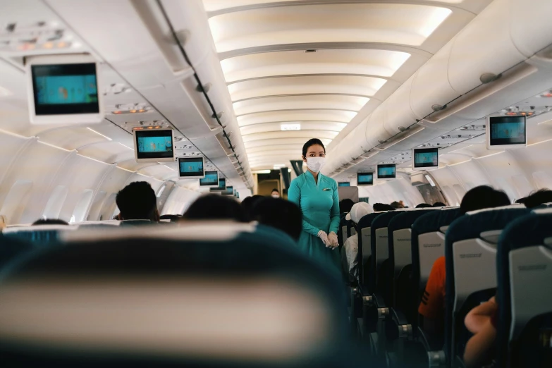 the cabin of an airplane with a person standing in the aisle and screen screens