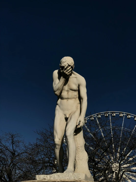 a statue next to a ferris wheel and a sky scr