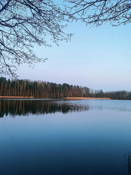 a lake with water, trees and sky in the background