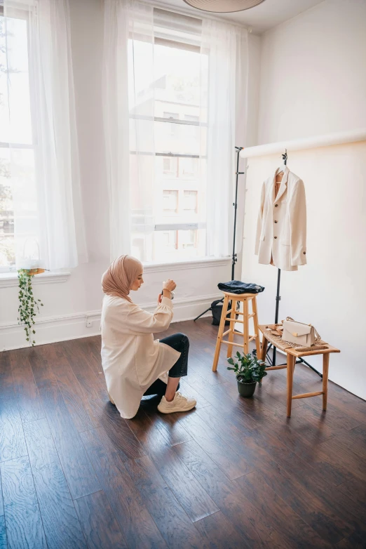 a woman kneeling down next to a wooden stool