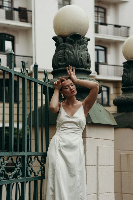 a woman poses in front of the gates of an iron fence