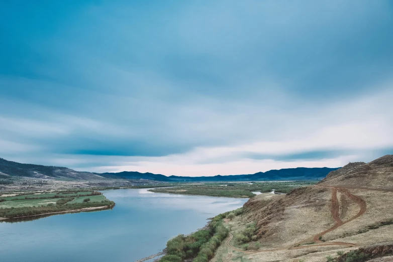 the mountains, a river and the cloudy sky are seen