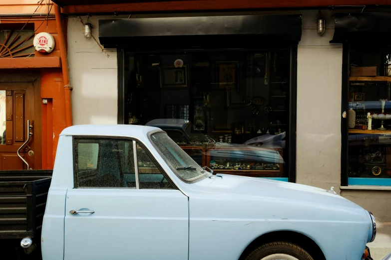 a car sitting in front of a storefront next to a person on the sidewalk