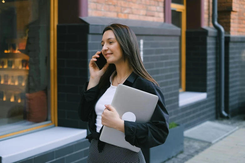 the woman is walking down the street talking on her cell phone