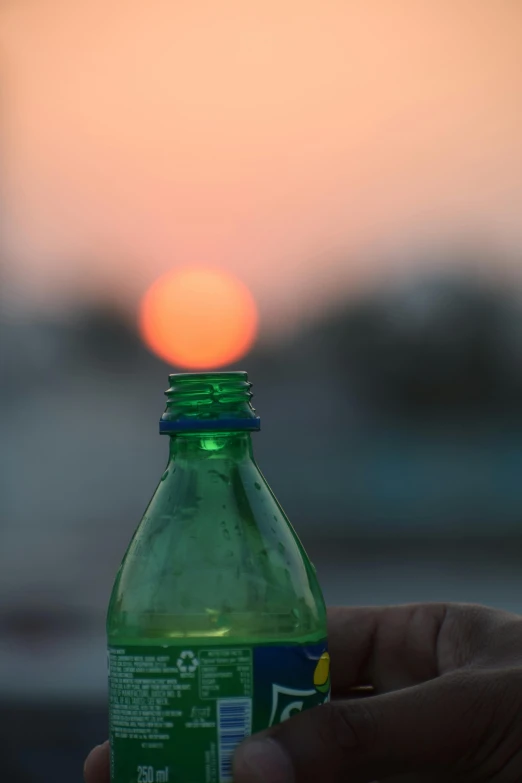 someone holding an empty green bottle of water