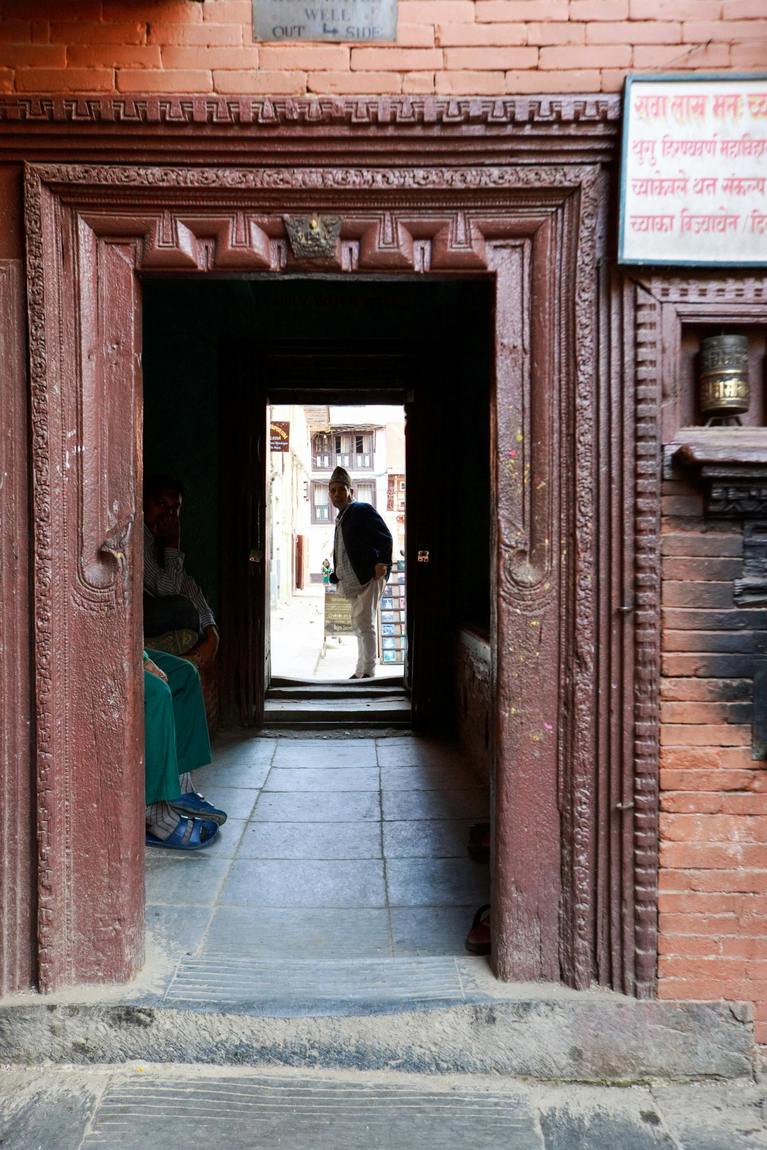 two men sit at the doorway to their homes