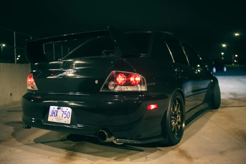 an black car parked on the side of a road at night