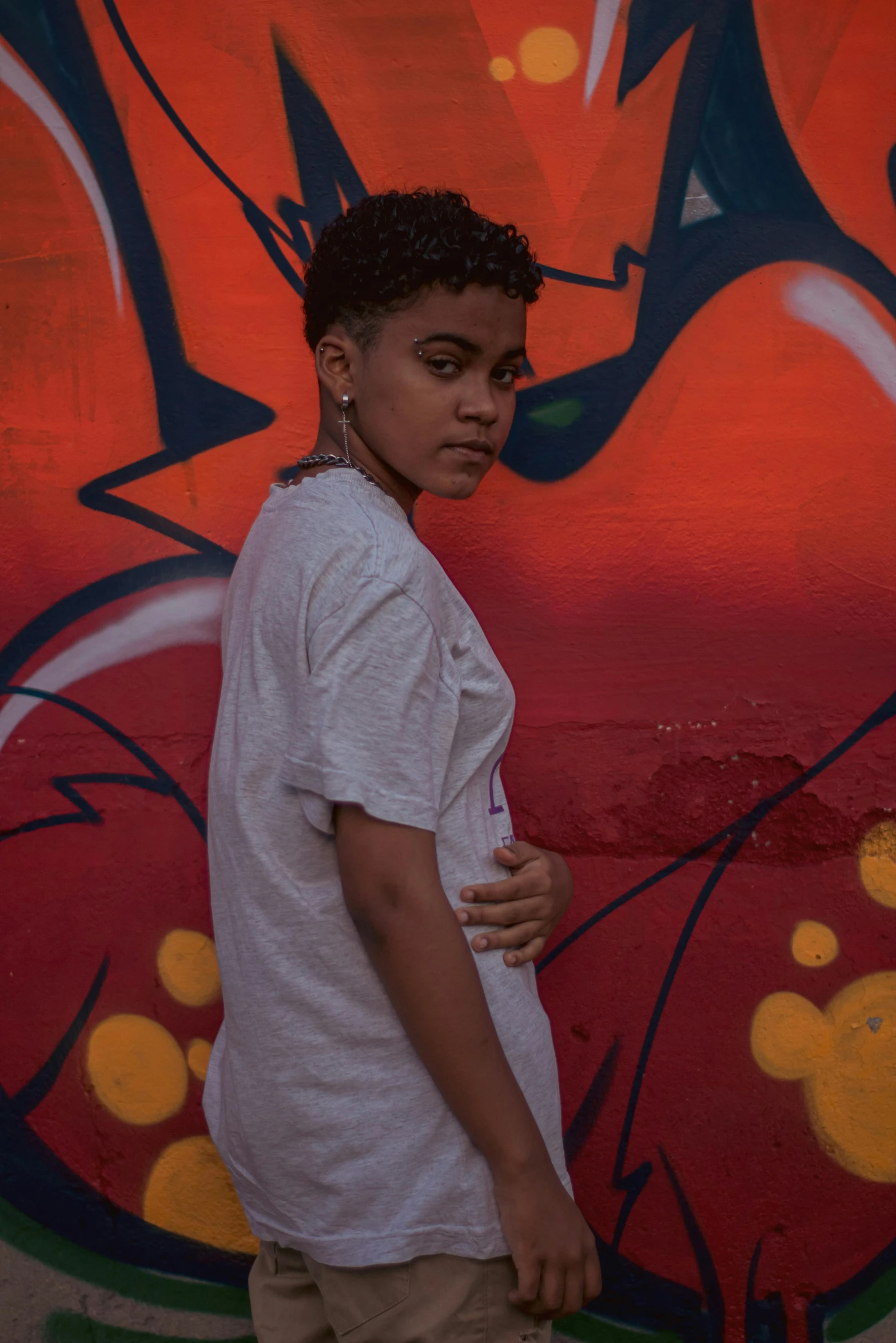 a young man stands in front of a graffiti wall