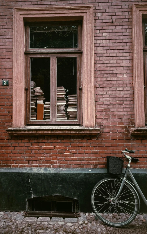 an old bicycle against a brick building with a broken window