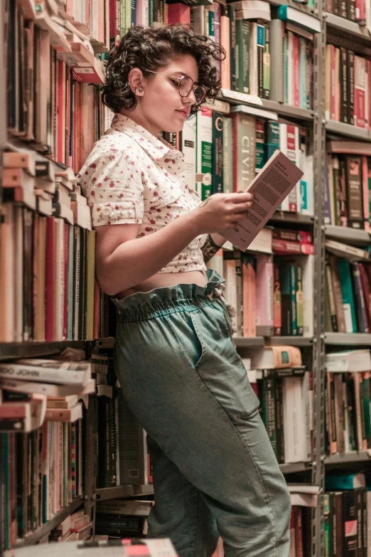 a woman standing in front of a bookshelf holding a book