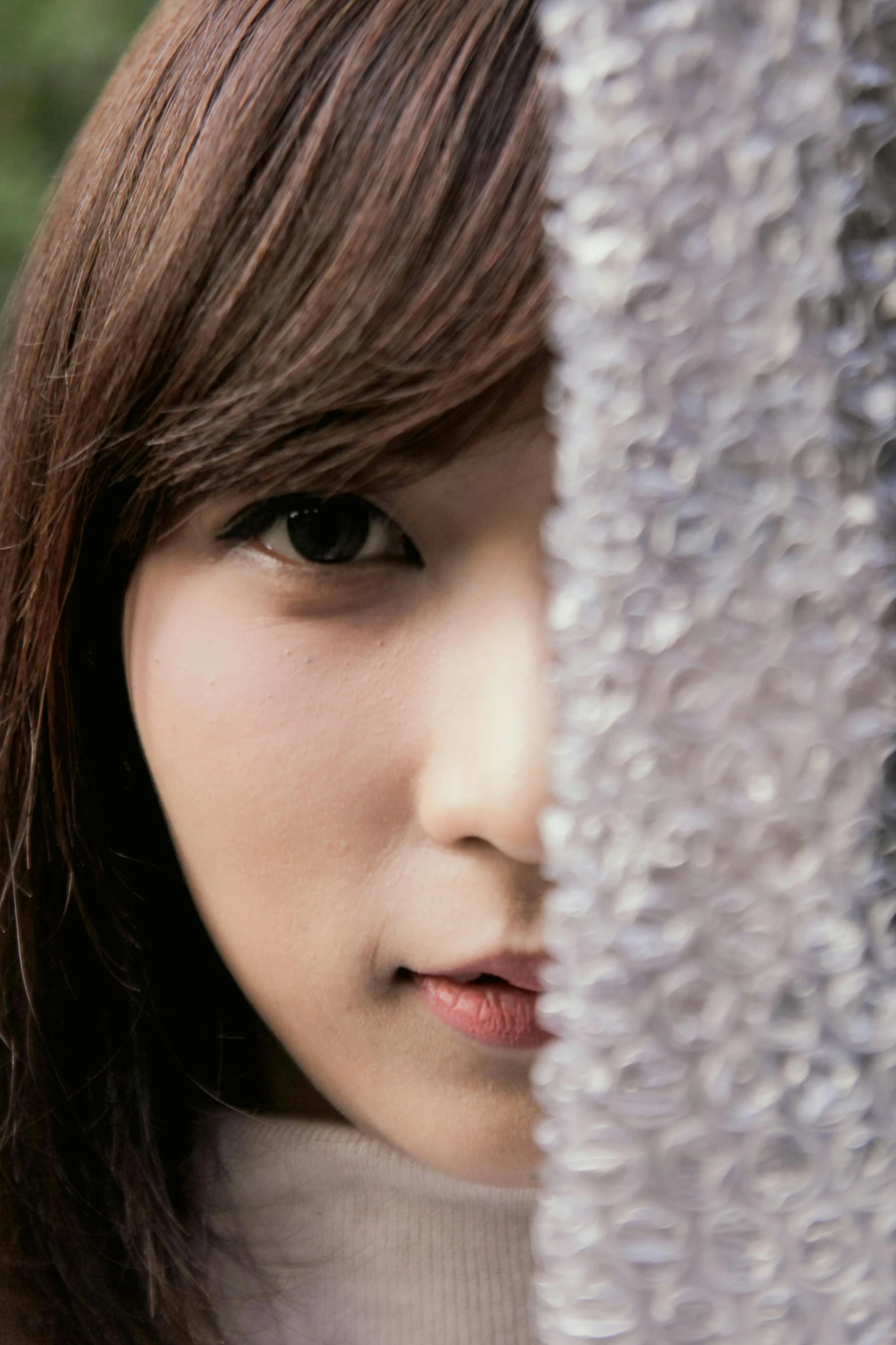 an asian woman peeking out from behind an ornamental screen