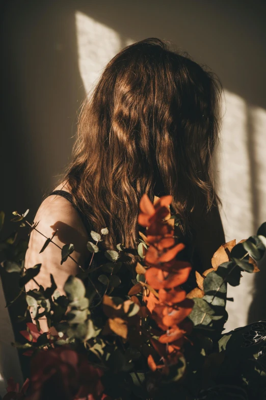 a person with long hair surrounded by leaves