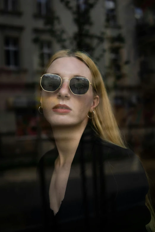 a woman wearing some dark colored shades in front of a building