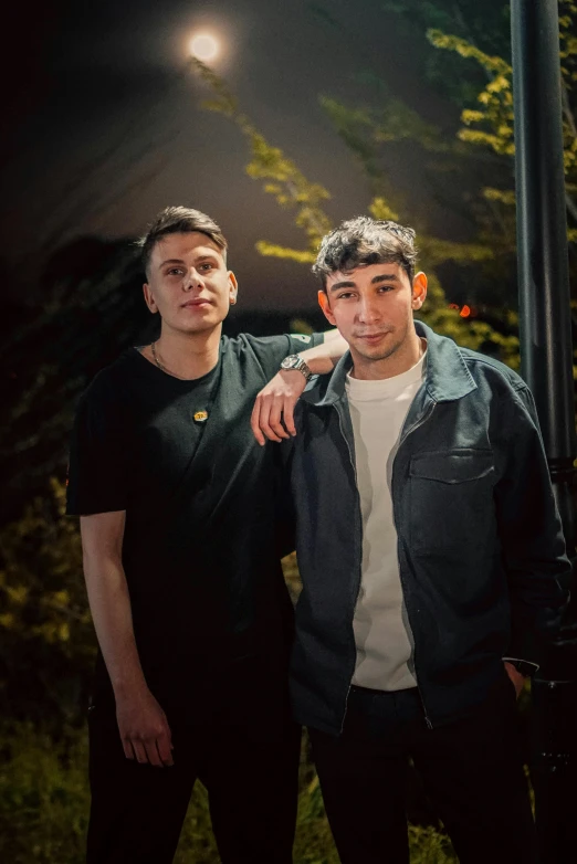 a couple of men posing for a picture at night