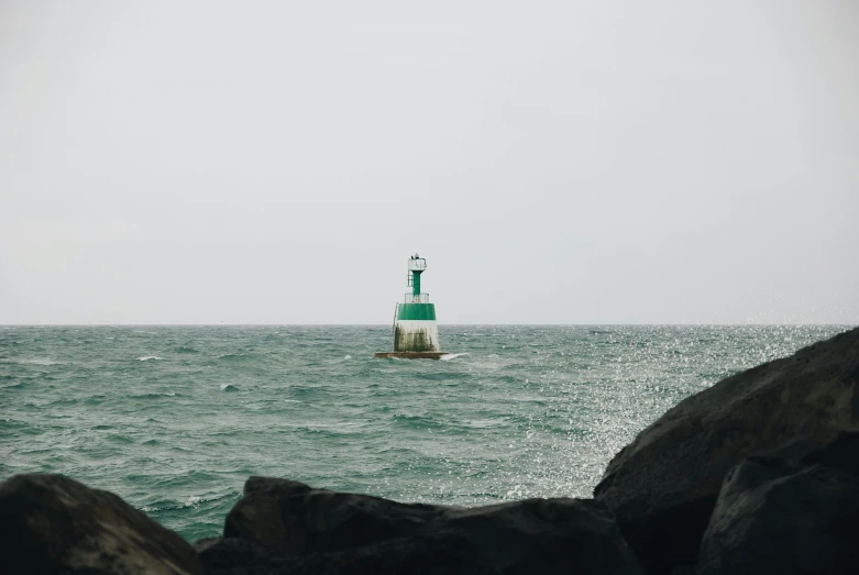 there is a small green light house in the water