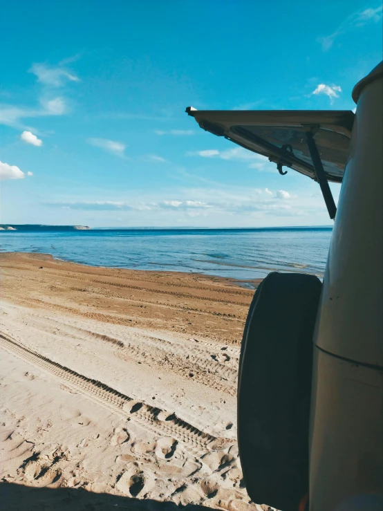 the view out the front window of an suv driving on a beach