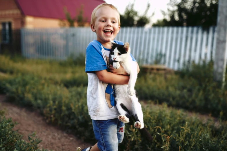  holding up a cat while standing in some grass