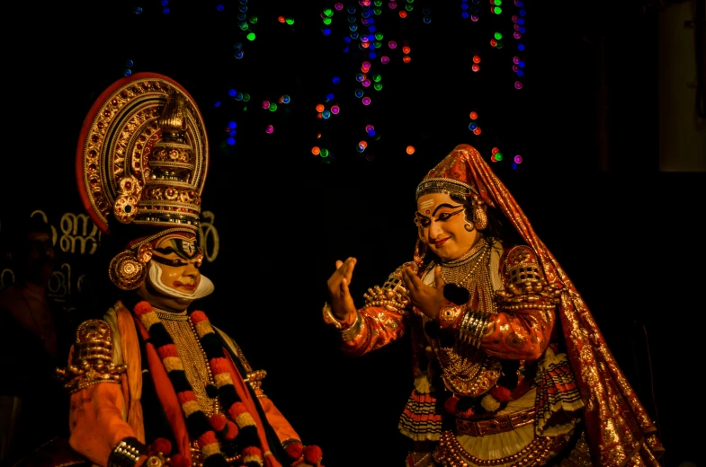 two people dressed in colorful clothing talking and dancing